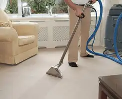 Carpet cleaning professional removing dirt and stains with a hot-water extraction tool in a home, Colorado Springs, CO.