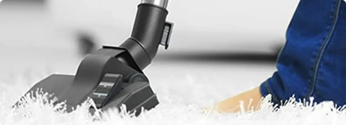 Close-up of a professional vacuuming a white carpet in Cripple Creek.